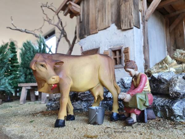 ein Bäuerin beim Melken einer Kuh als Krippenfigur aus Kunstharz